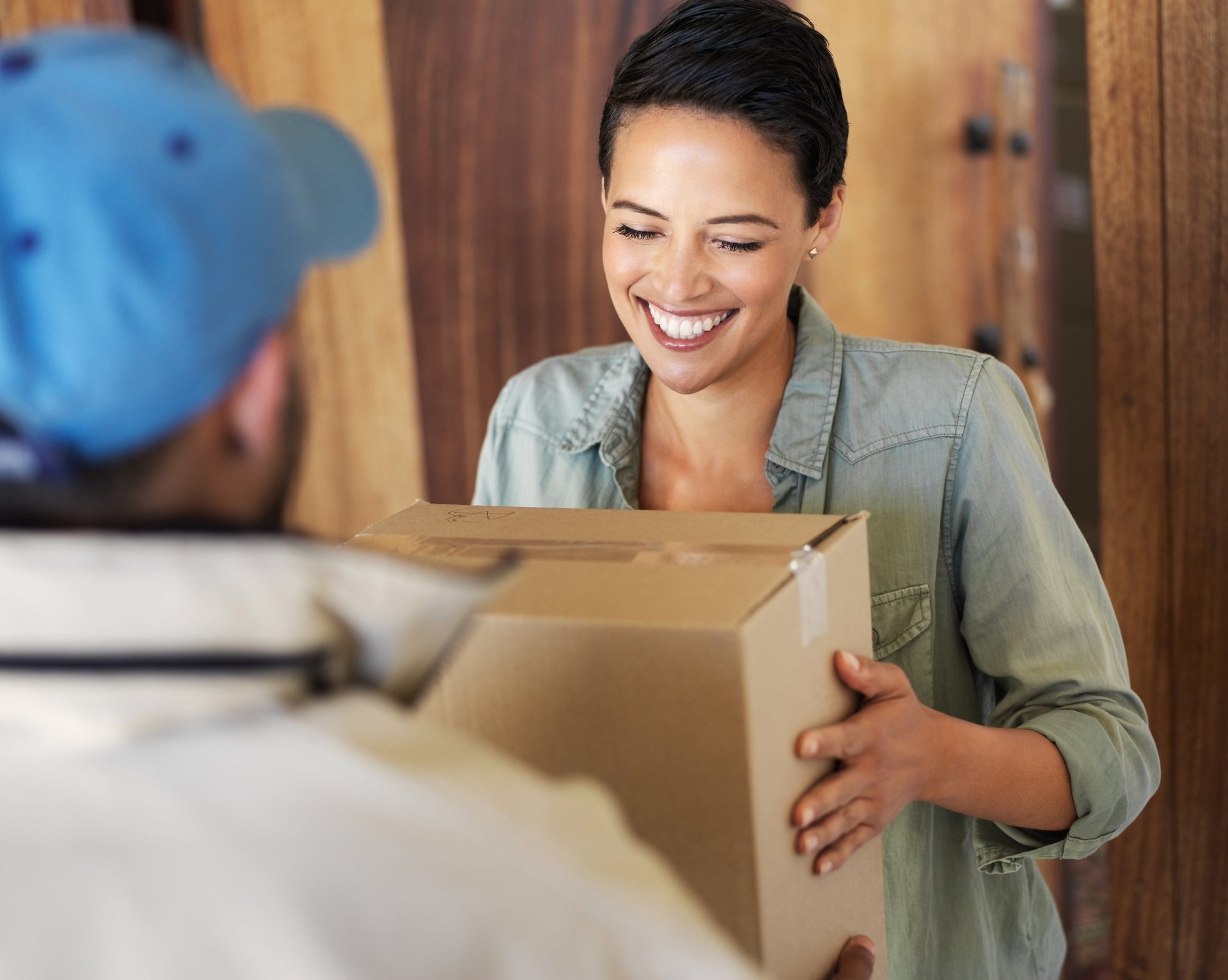 Smiling person receiving a package from a courier at the door, well-cared delivery in perfect condition